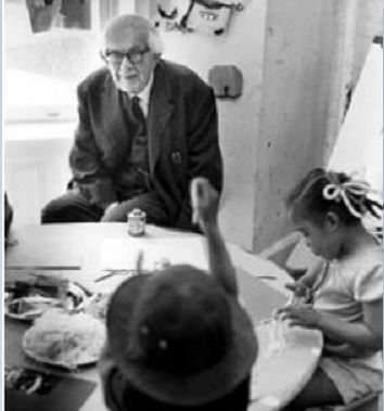A photo of Jean Piaget (with children in classroom)